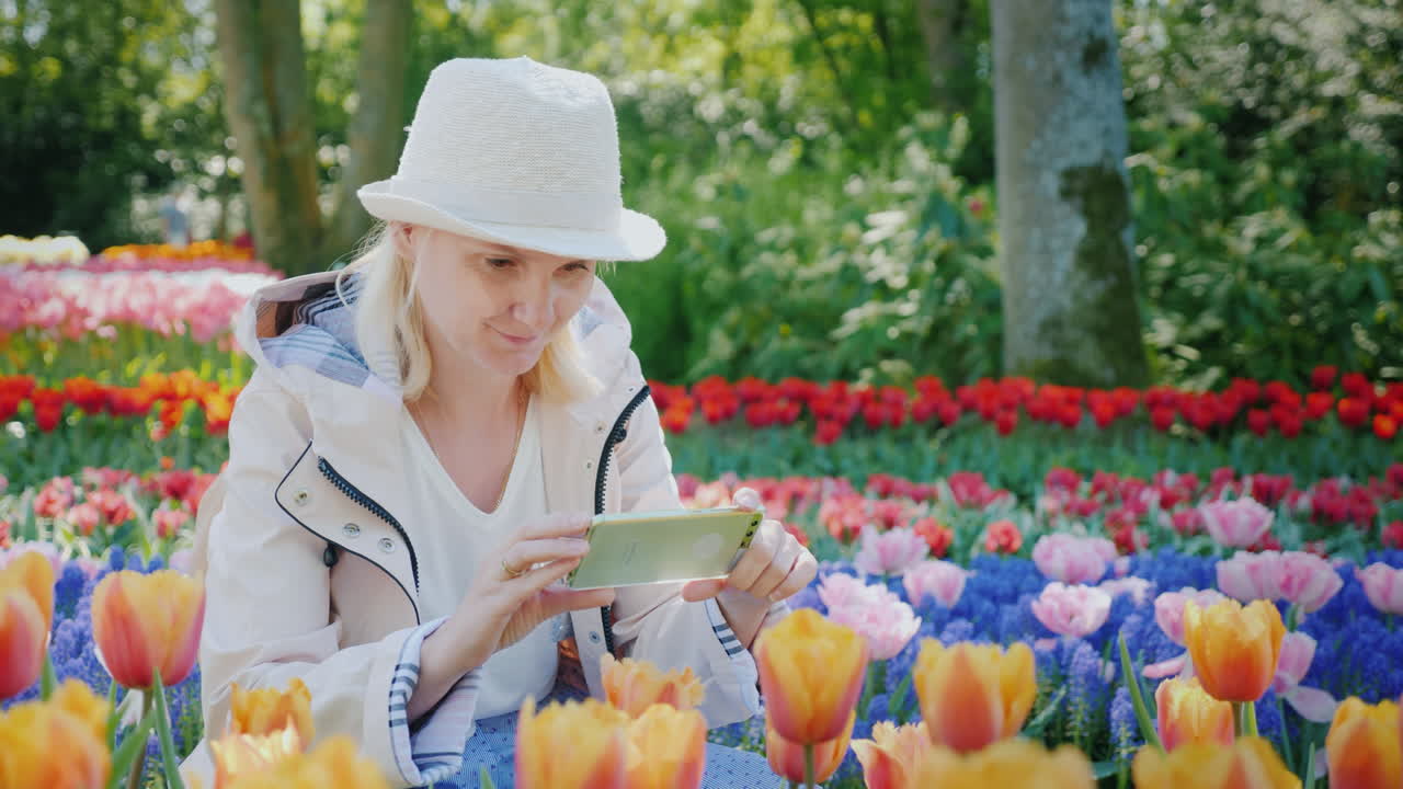 mulher em seu telefone cercada por tulipas