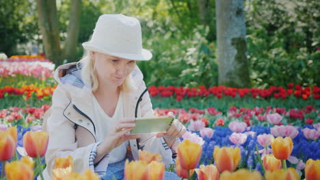 mujer en su teléfono rodeada de tulipanes