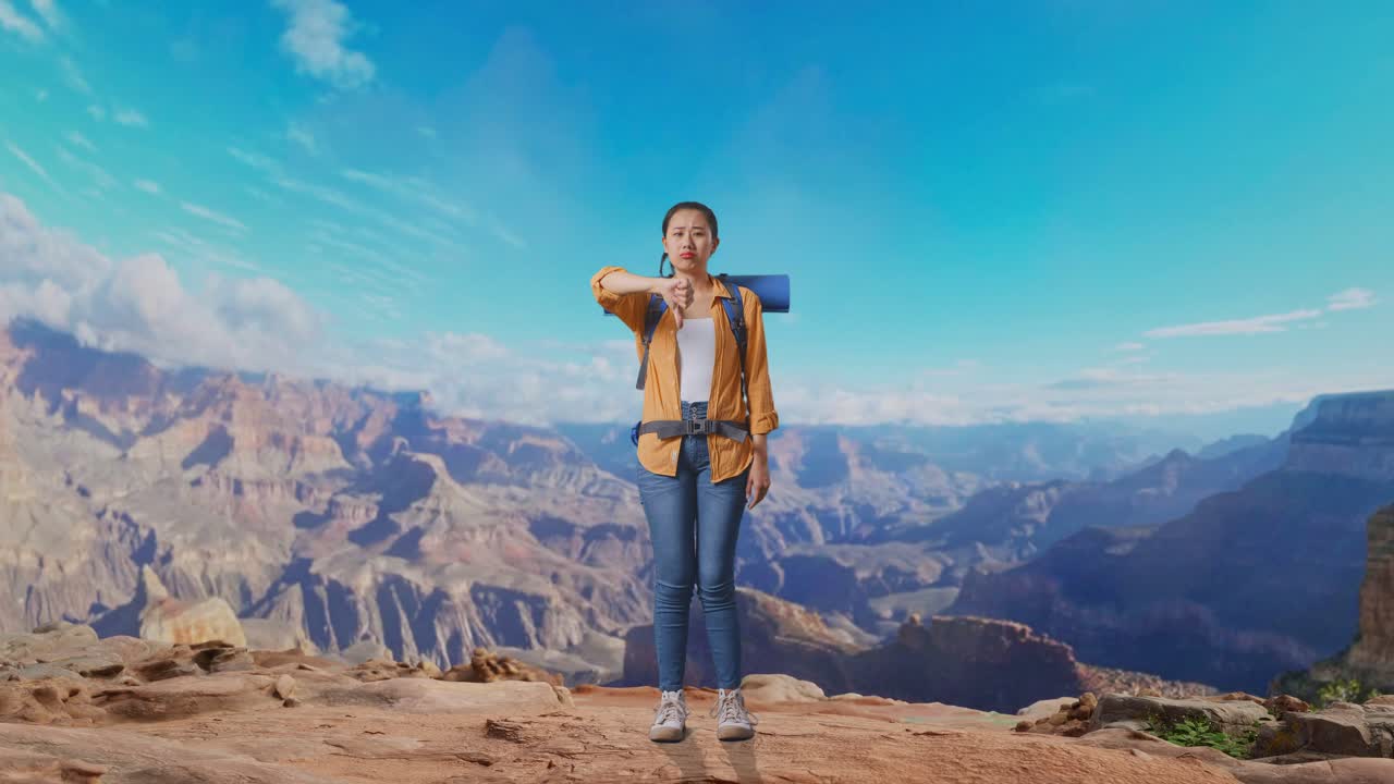 Full Body Of Asian Female Hiker With Mountaineering Backpack Showing Thumbs Down Gesture While Traveling At The Top Of Mountain