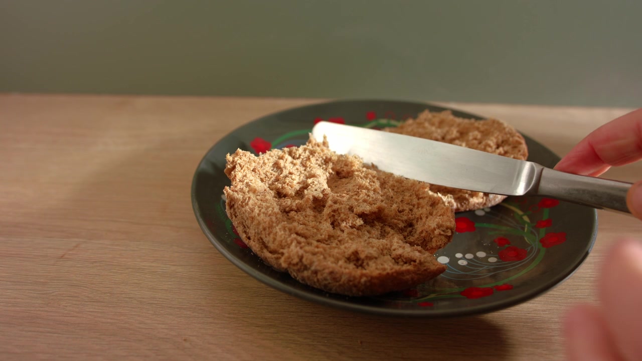 Hand cutting brown wholemeal bread for sandwich close up 4k slow motion shot selective focus