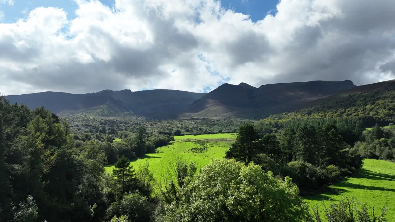코메라그 산, 워터포드 항공기, 푸른 목초지 위의 산으로 날아가는 여름 저녁
