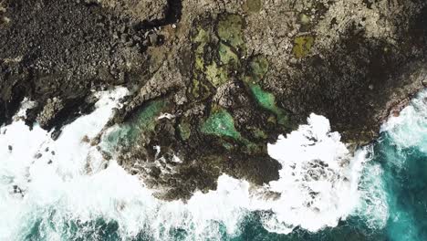 Drone-Shot-directly-above-waves-crashing-on-the-Makapu'u-Tidepools-off-the-rocky-coast-of-Oahu,-Hawaii,-USA