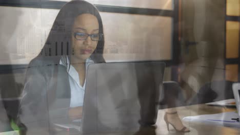 Animation-of-people-walking-over-african-american-businesswoman-using-laptop-at-office