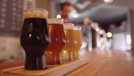 glasses of artisanal beer on a bar counter with barman pouring draft beer