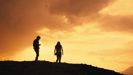 silhouettes of young couple on mountain photograph orange yellow sunset