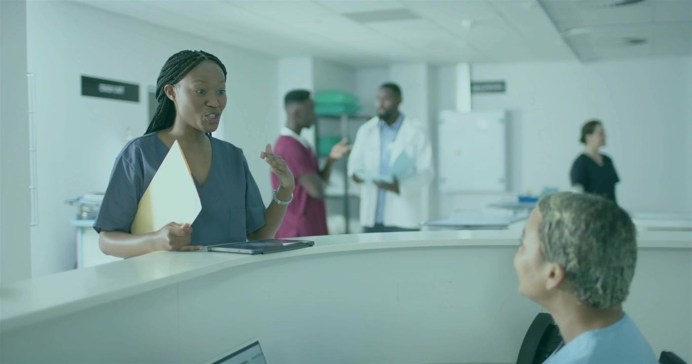 En sjuksköterska talar och initierar vågformer och data runt en surfplatta, medan hon förklarar patientinformation för sin patient.