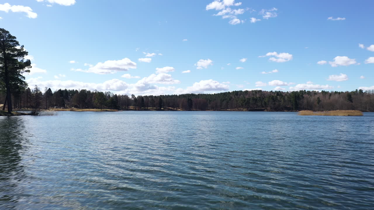 Drone aérien d'un lac sous un ciel avec un travelling rapide sur l'eau agitée et le reflet des nuages à la surface du lac