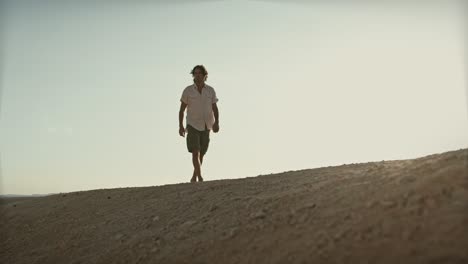 Video-Cinematográfico-De-Un-Hombre-Vestido-Con-Ropa-De-Verano-Caminando-Por-El-Desierto-En-Un-Día-Extremadamente-Caluroso-En-Verano.