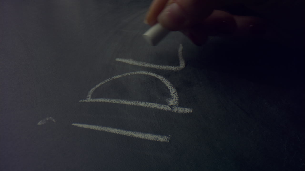 mujer con una tiza en la mano. persona irreconocible escribiendo una palabra de idea en la pizarra