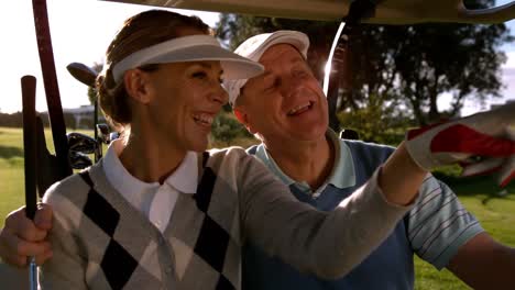 golfing couple sitting buggy looking around the course