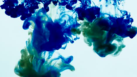 4k footage of green and blue colorful ink drops in water, isolated abstract background. pouring ink in water. underwater paint mix. slow psychedelic dye swirls, colored smoke explosion. splashing, floating liquid