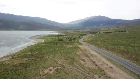 Long-road-adjacent-to-reservoir-leading-to-vast-mountain-range