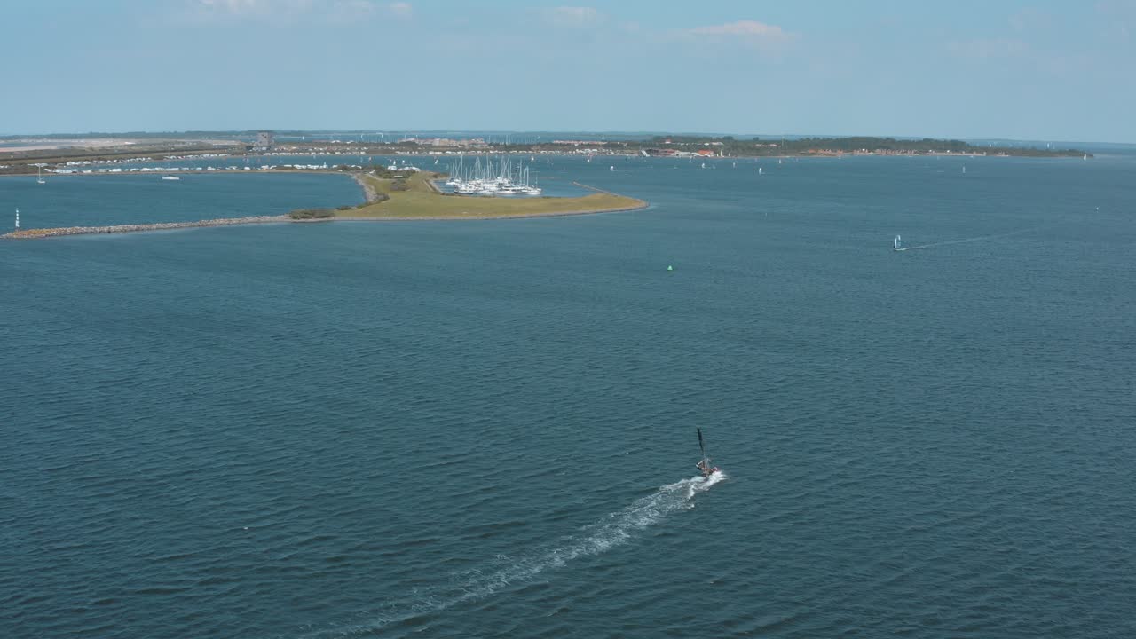 drone - toma aérea de un surfista en un mar azul, ondulado y ventoso en un día soleado con nubes blancas en una isla, 25p