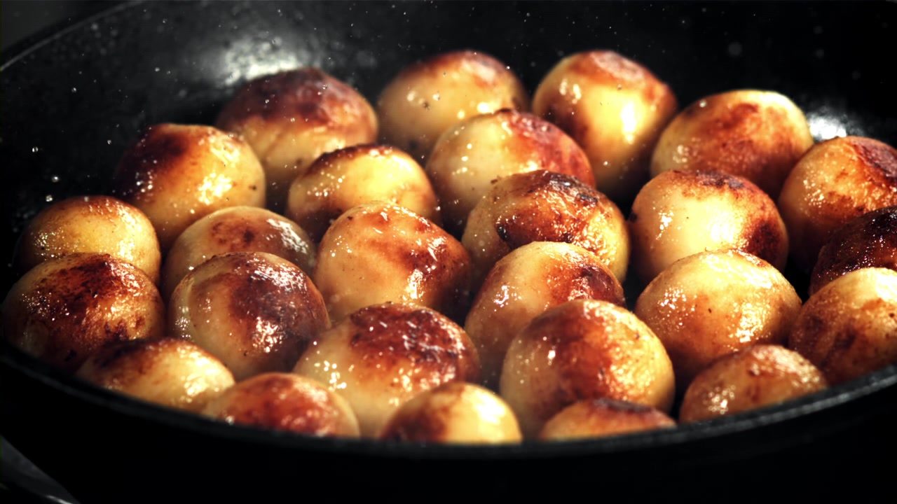 Primo piano di piccole patate che friggono in una padella calda.
