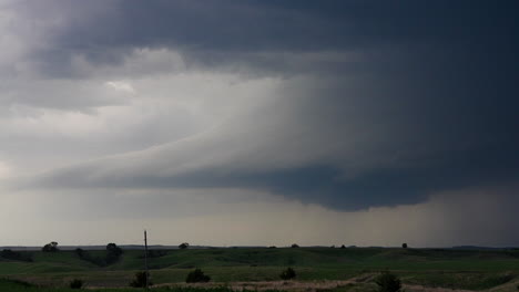dramatic supercell storm cloud over green rolling hills