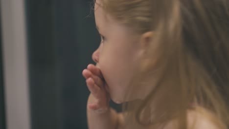 little girl washes mouth with water at mirror in bathroom