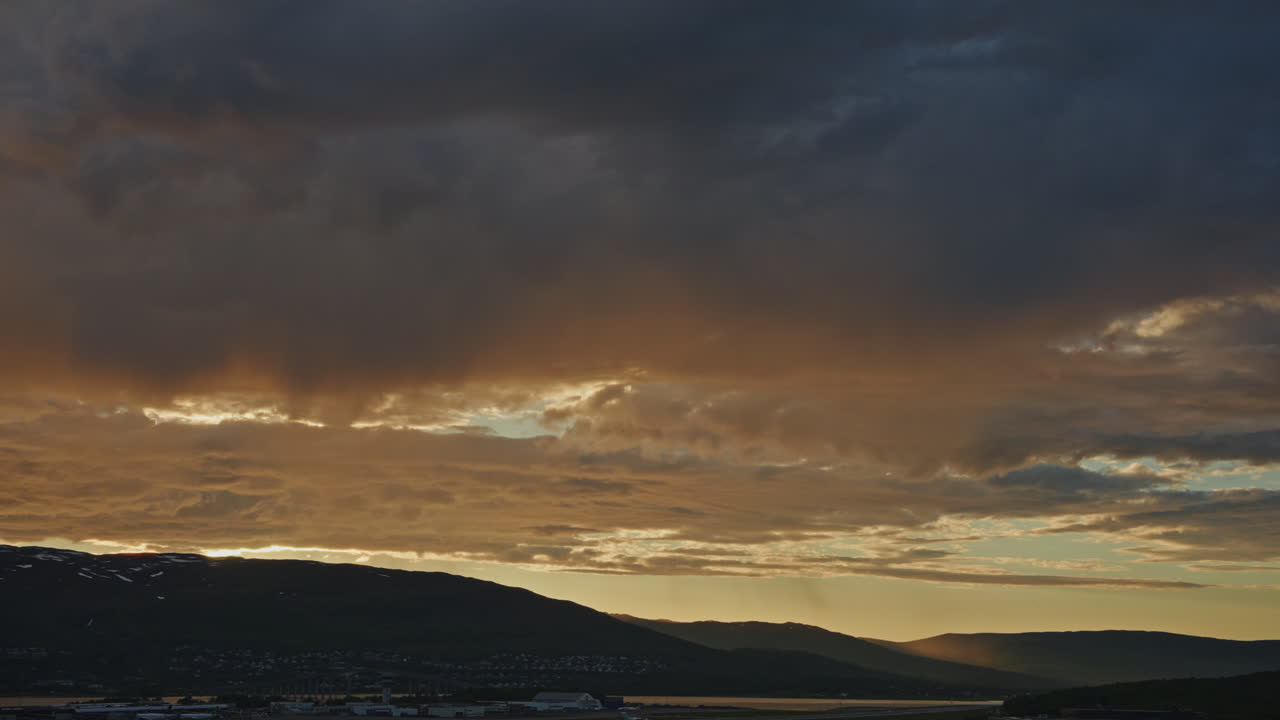 Midnight sunset over the Norwegian Fjords in Tromso.
Arctic golden hour twilight over the snowy mountains and traveling clouds. Picturesque nordic landscape.