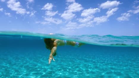 little red hair girl relaxing by floating with open arms and letting herself be lulled by ocean movement