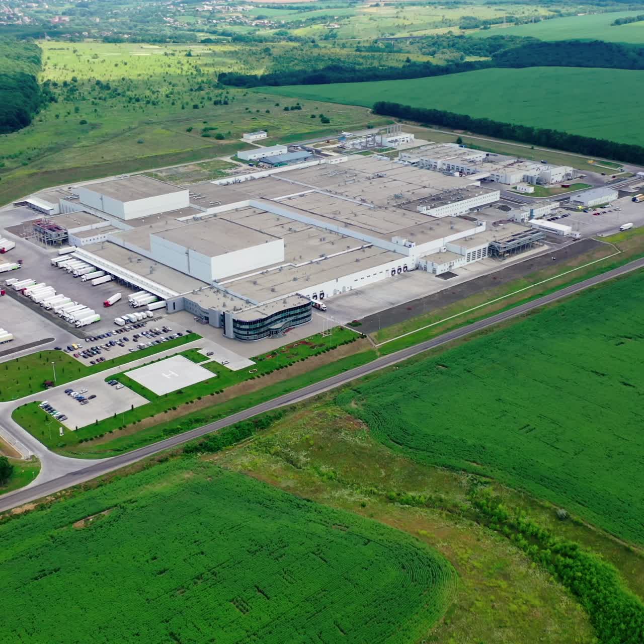 Modern industrial plant near the road among green nature. Large territory on innovative factory on beautiful green landscape. Aerial view. Top down