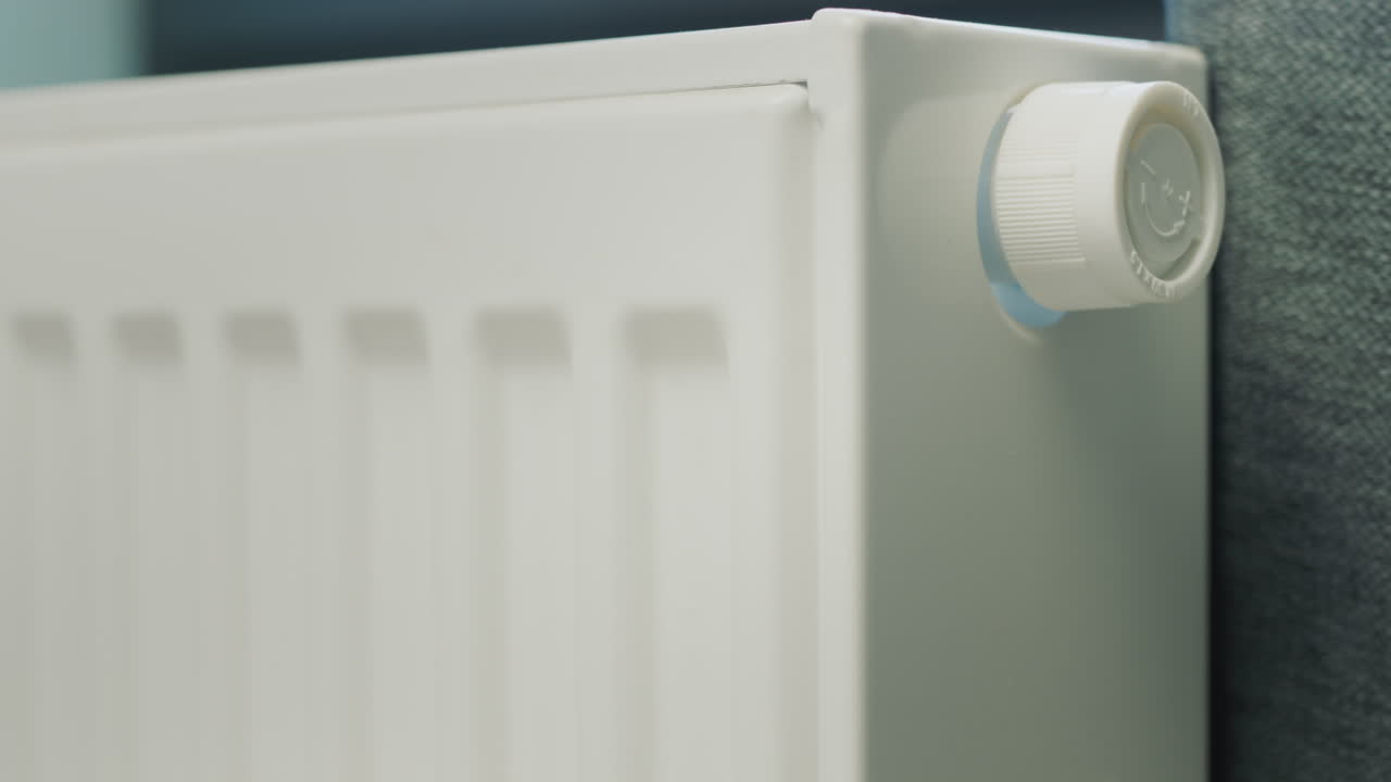 A man's hand regulates the temperature on a heating radiator. Conservation of energy resources in a private house