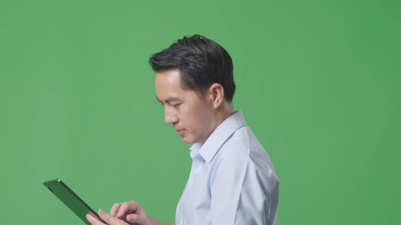 스튜디오에서 녹색 화면 배경에서 는 동안 태블릿을 사용하는 아시아 사업가의 측면 뷰 클로즈업