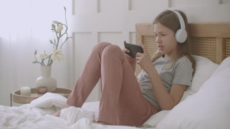 child girl is using smartphone playing game online after waking up in sunday morning internet addiction of schoolchildren