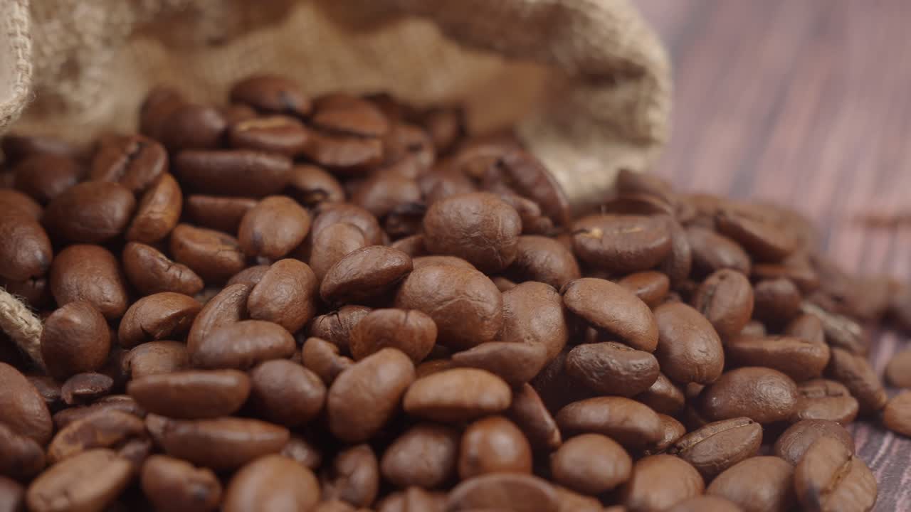 Fagioli di caffè arrostiti che si riversano da un sacco di burlap