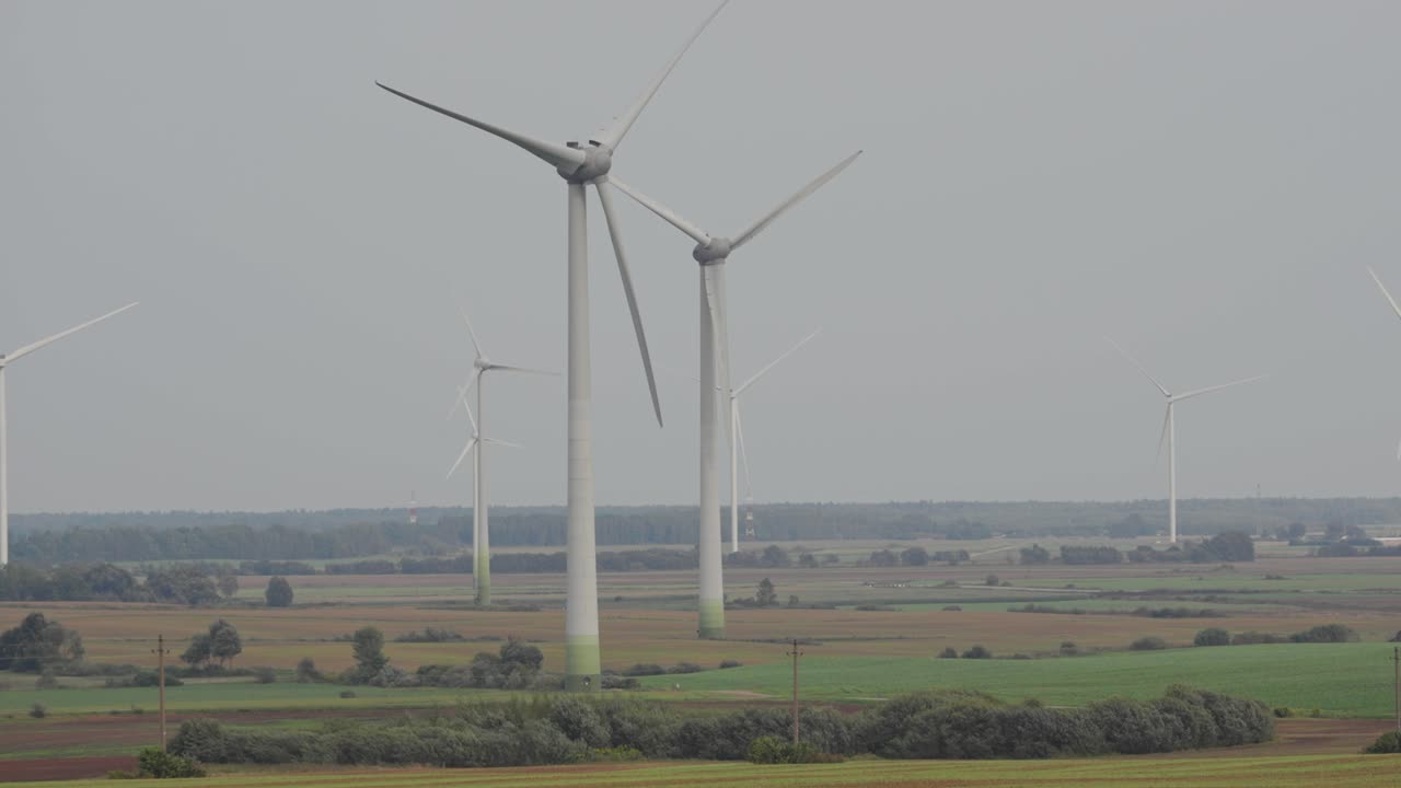 Spinning wind turbines scattered across a wide rural landscape, showcasing clean and renewable energy sources in a scenic countryside setting