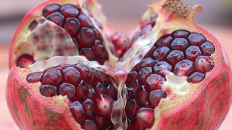 a close-up view of a split pomegranate revealing juicy, glossy seeds encased in a transparent membrane, showcasing nature's vibrant red colors