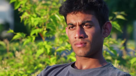 portrait of single young indian man looking concerned, outdoor, circle pan