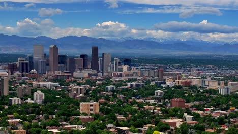 Summer-in-downtown-Denver-aerial-drone-pan-left-motion-front-range-Colorado-mountain-peak-foothills-landscape-Flat-irons-Red-Rocks-city-skyscrapers-neighborhood-homes-blue-skies-clouds-spring