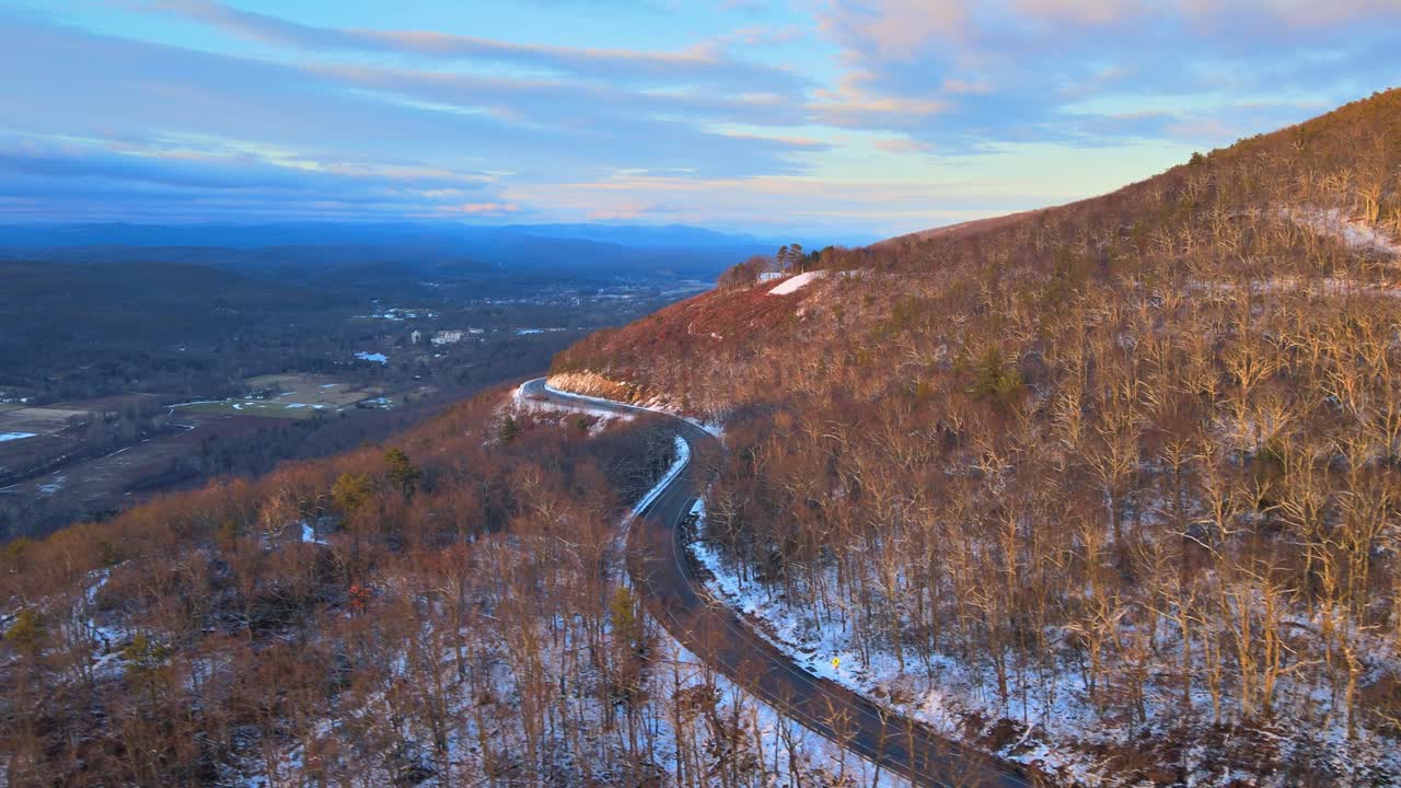 un camino de montaña pintoresco y sinuoso durante el invierno con nieve ligera en las montañas apalaches