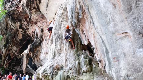 climber ascends limestone cliff in krabi, thailand