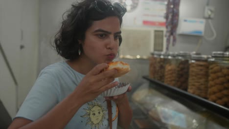 Plano-Medio-De-Una-Joven-India-Que-Disfruta-De-Una-Deliciosa-Experiencia-De-Degustación-De-Pasteles-En-Una-Tienda-De-Dulces-Dentro-De-Un-Supermercado.