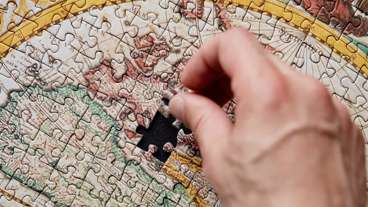 Hand putting down puzzle piece closeup. Jigsaw assembling on black background