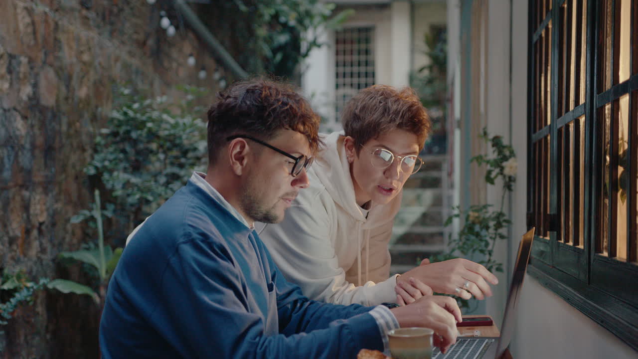 Colleagues Discussing Project on Laptop in a Small Backyard