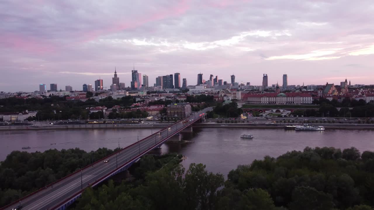 Imagens de drone do horizonte de Varsóvia e do rio Vístula com uma ponte em um pôr do sol mágico e rosa, com o drone avançando