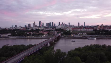 Imágenes-De-Drones-Del-Horizonte-De-Varsovia-Y-El-Río-Vístula-Con-Un-Puente-Sobre-Una-Mágica-Puesta-De-Sol-Rosa-Moviendo-El-Dron-Hacia-Adelante