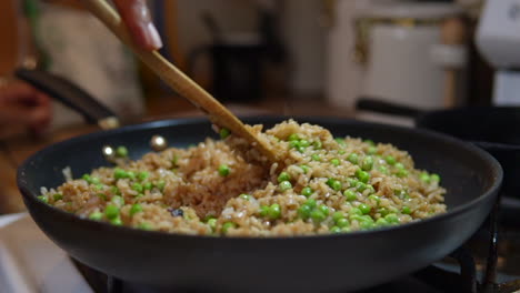 stirring fried rice and peas in a skillet, pan or wok - slow motion