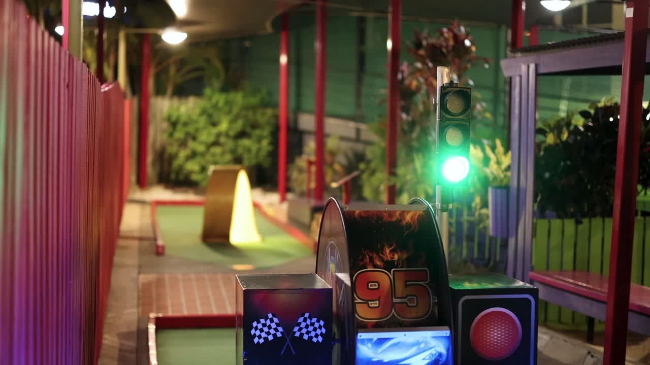 A vibrant miniature golf course features animated traffic lights and colorful lighting, creating a playful and dynamic atmosphere