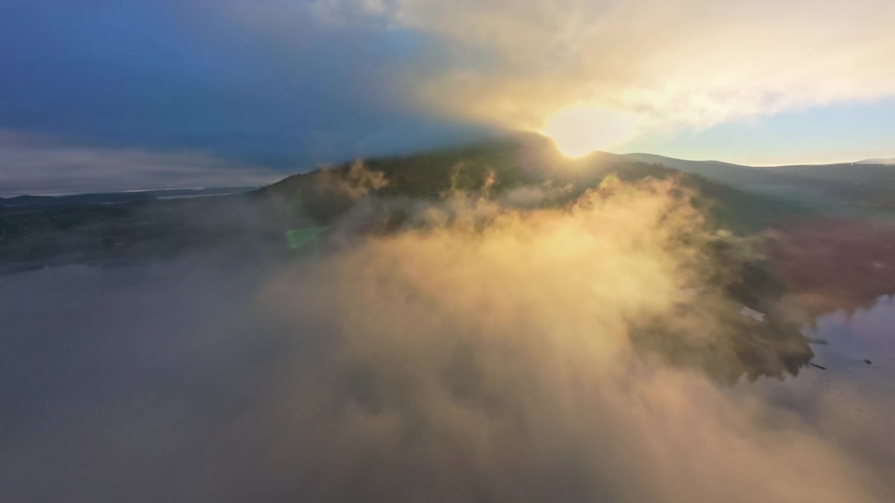 Vista aerea dell'alba dorata su un lago di montagna nebbioso