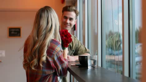 young man giving rose to woman in cafe 4k