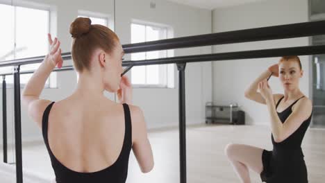 Caucasian-female-ballet-dancer-preparing-for-dance-class-in-a-bright-studio