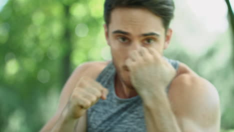 young kickboxer training punch at outdoor workout in park. portrait of boxer man