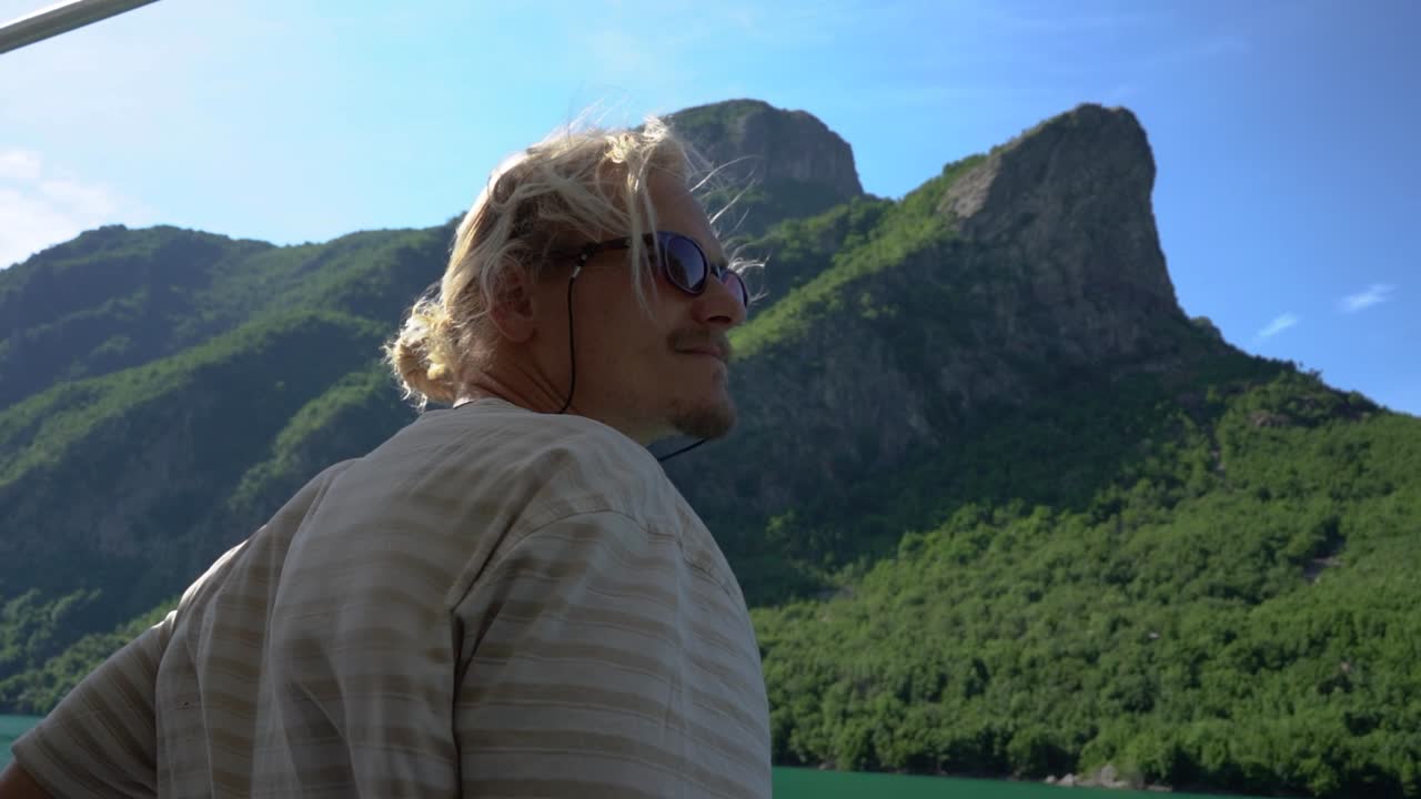 Young male tourist sightseeing onboard a boat on the scenic Komani Lake in Northern Albania, Europe