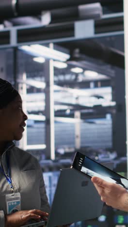 vertical video data scientists working together in server room, reviewing neural network code