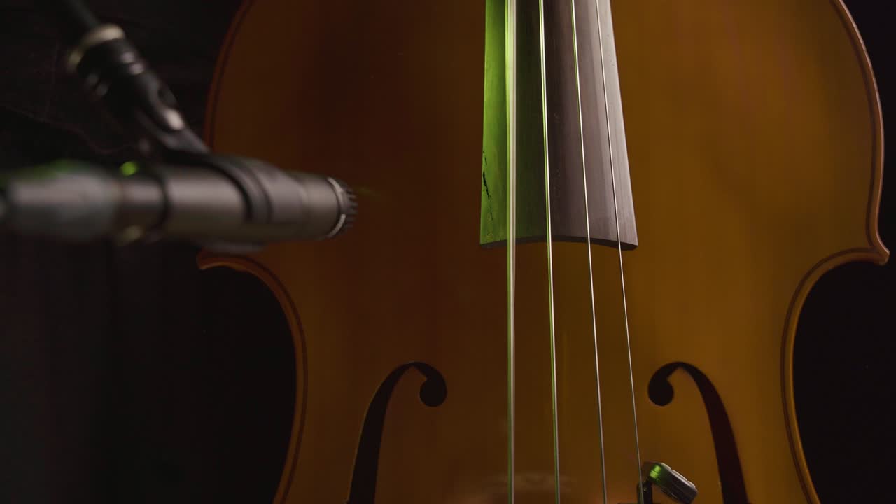 manos masculinas tocando el bajo mientras graban con un micrófono en primer plano