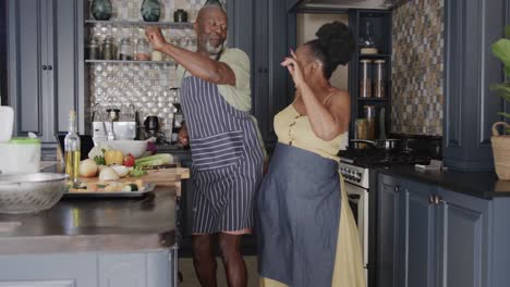 happy senior african american couple dancing in ktichen in slow motion