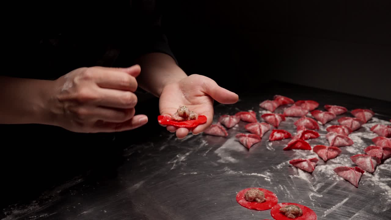 Close-up of Hands Making Red Dumplings with Meat Filling