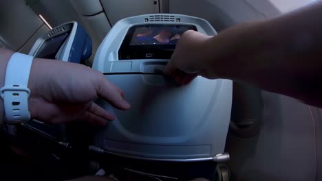 extreme wide of a set of hands folding up a tray table on an airplane and locking it to the seat